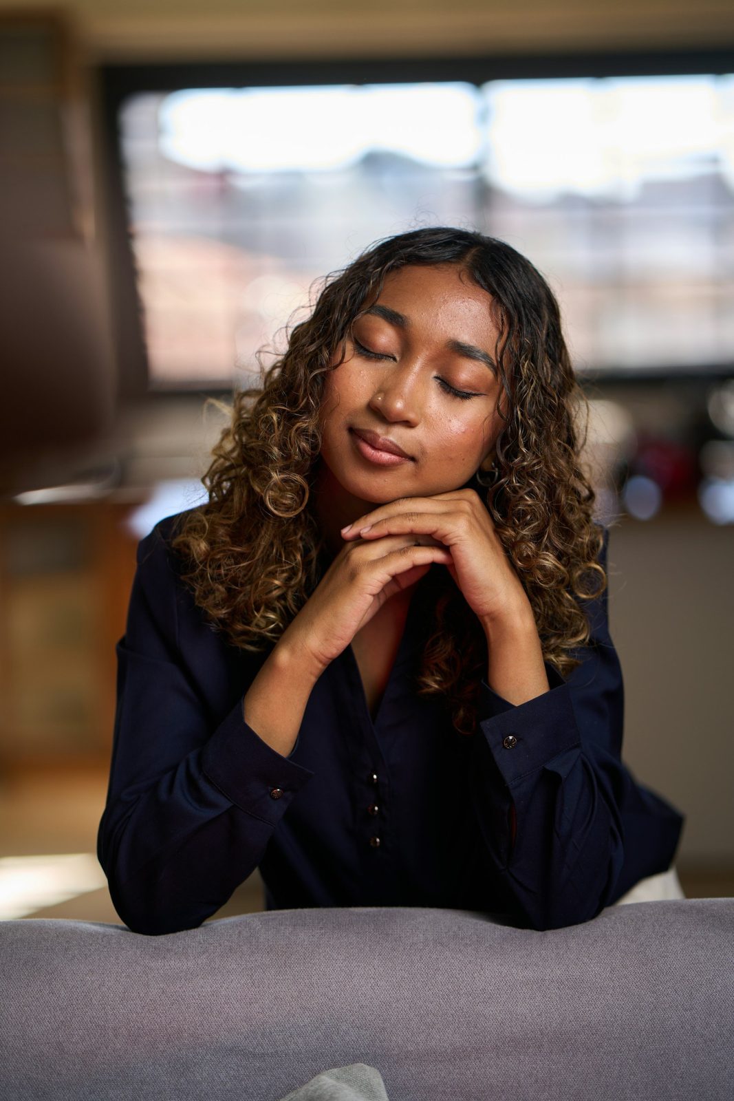Woman with curly hair resting her chin on her hands